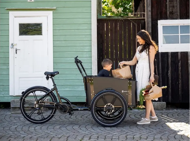 Förälder lastar matkassar i en Cargobike Delight med ett barn i lådan